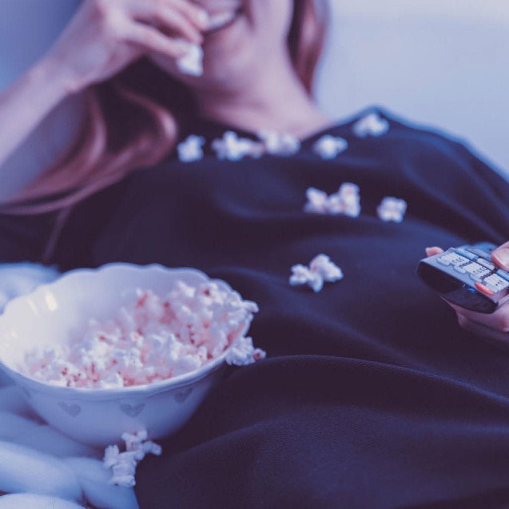 woman watching tv with popcorn spilled on her