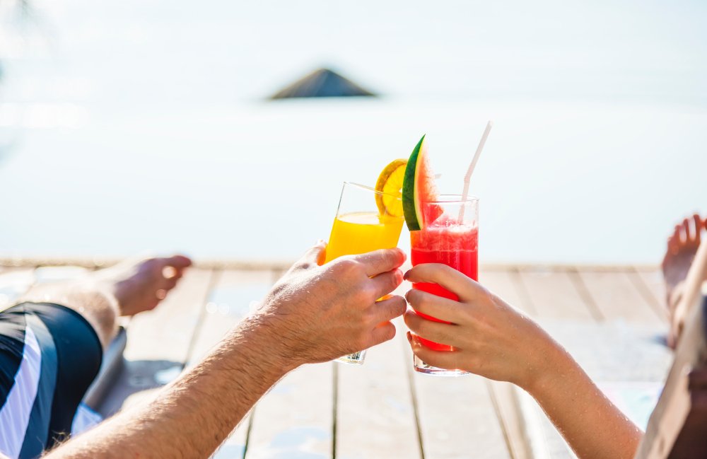 cheers of two beverages on a beach