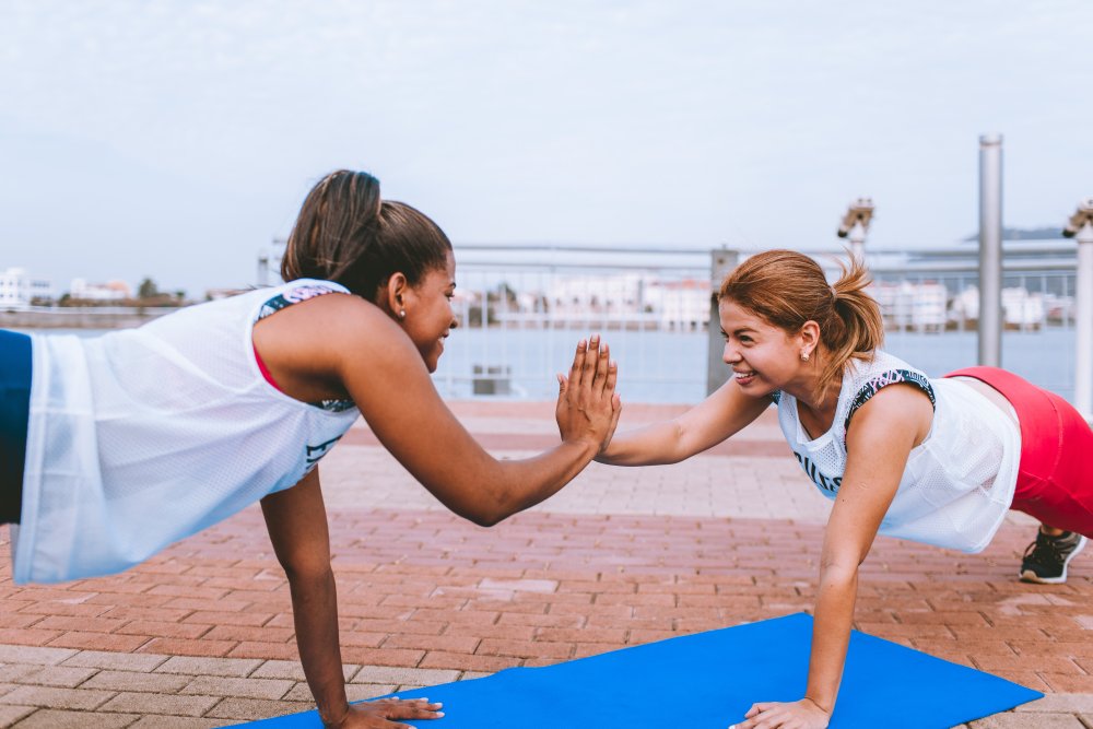 two women in plank position near water front