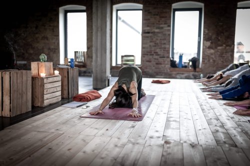 woman teaching yoga class with everyone in downward dog