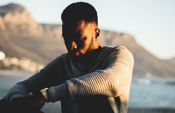 man in sweater near water contemplating life