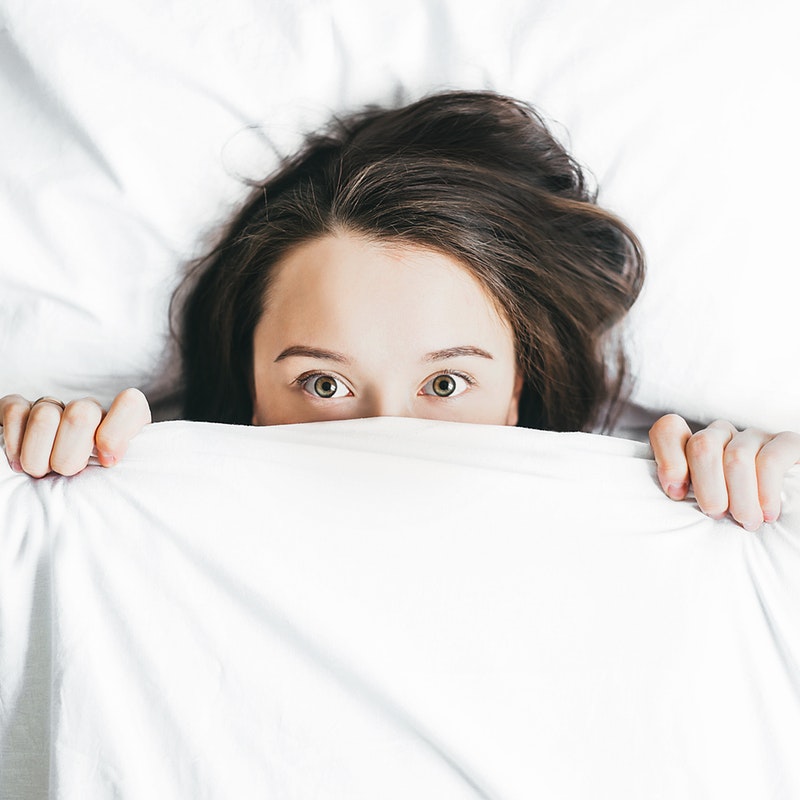 woman peeking out from under the covers