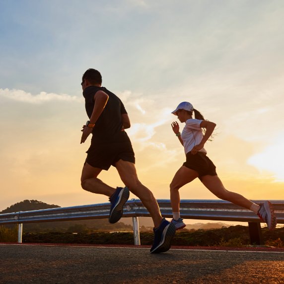 man and woman running on coastal highway