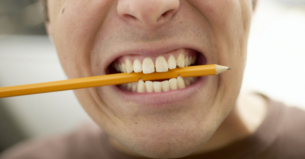 man biting pencil