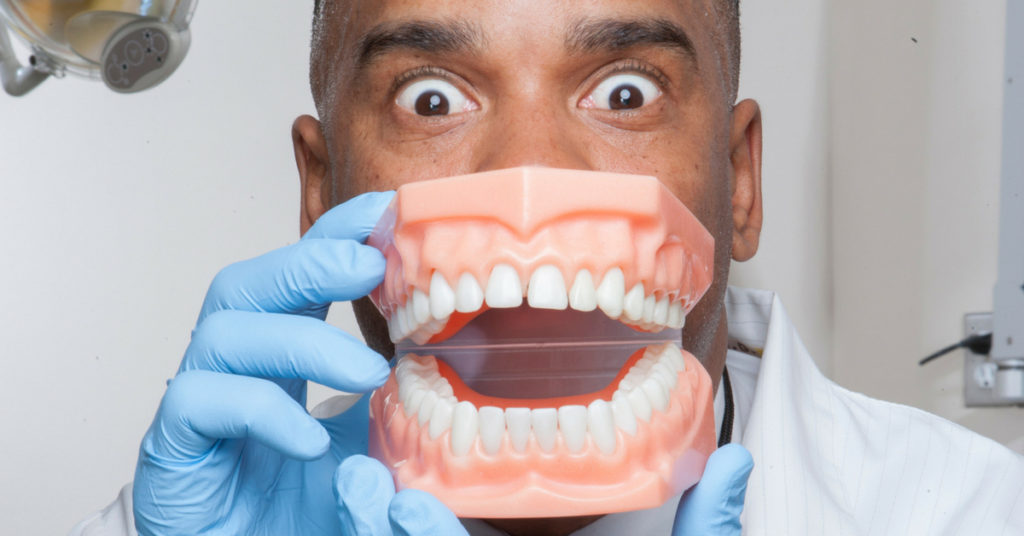 Dentist holding mouth mold up being funny