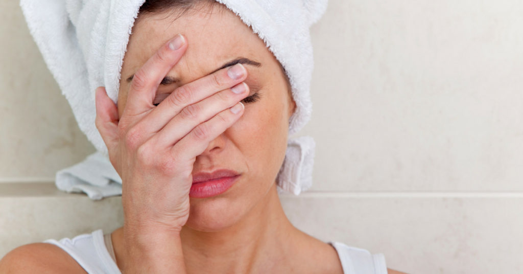 Woman clasps face frustrated with towel on head